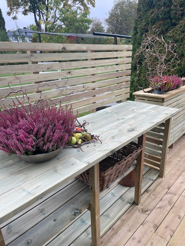 Nærbilde av utekjøkken i spiler med hyller og blomster på benken