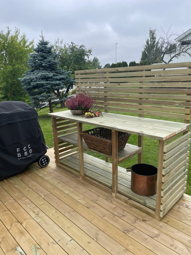 Utekjøkken i tre med arbeidsbenk, hyller og spilevegg på terrassen